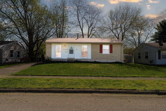 view of front facade with a lawn and brick siding