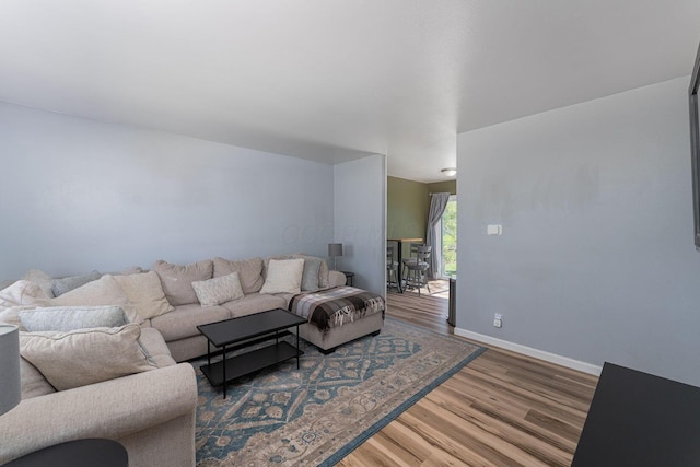 living area with baseboards and wood finished floors