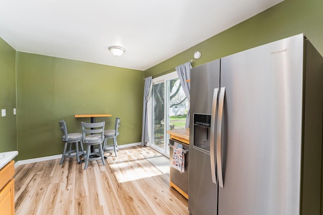 kitchen with wood counters, baseboards, appliances with stainless steel finishes, and light wood-type flooring