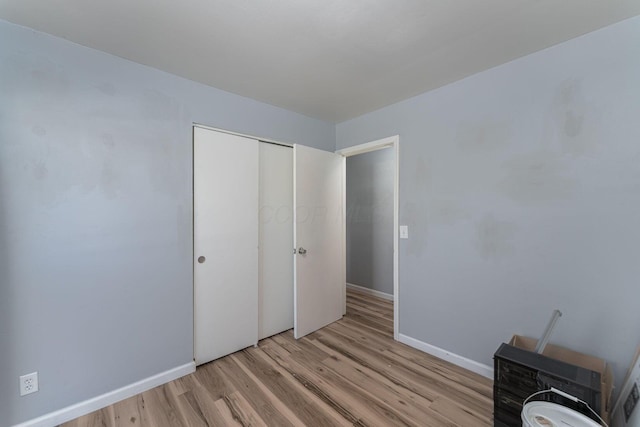 bedroom featuring baseboards, light wood-style floors, and a closet