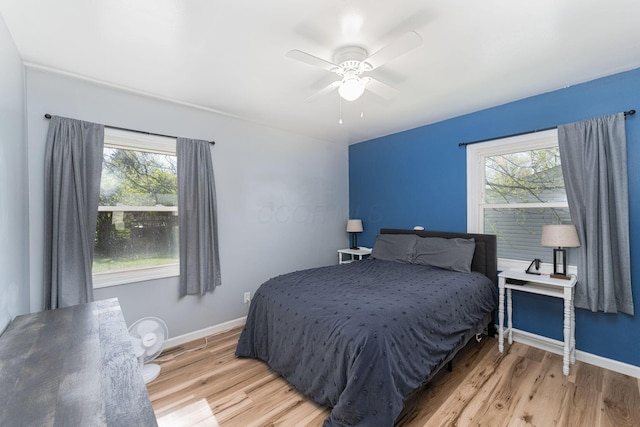 bedroom with light wood-style flooring, baseboards, and multiple windows