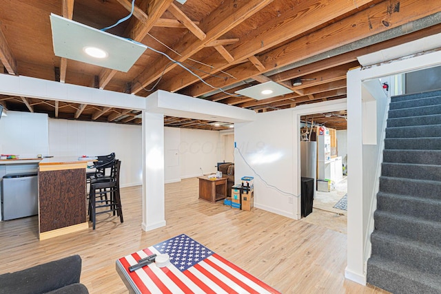below grade area with refrigerator, wood finished floors, and stairway