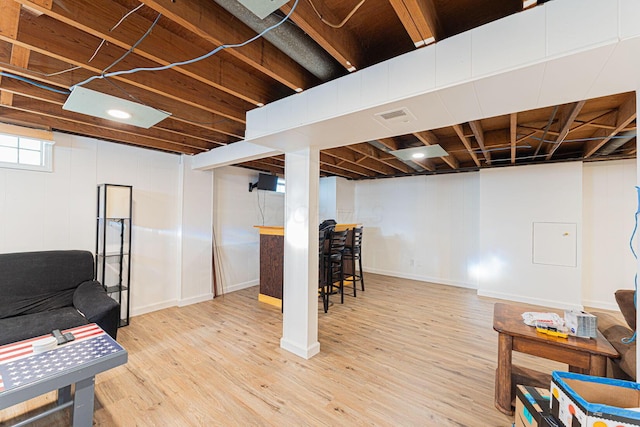 below grade area with wood finished floors, visible vents, and a bar