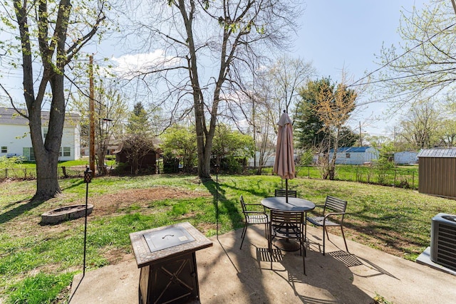 view of patio / terrace featuring a fenced backyard, a storage shed, central air condition unit, outdoor dining space, and a fire pit