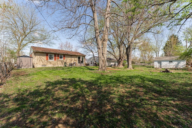 view of yard with a fenced backyard, an outdoor structure, and a storage unit