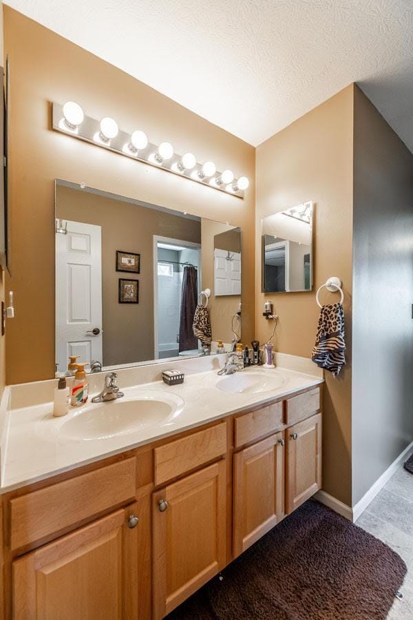 8181 Trail Lake Dr, Powell, OH 43065 - bathroom featuring double vanity, a textured ceiling, and a sink