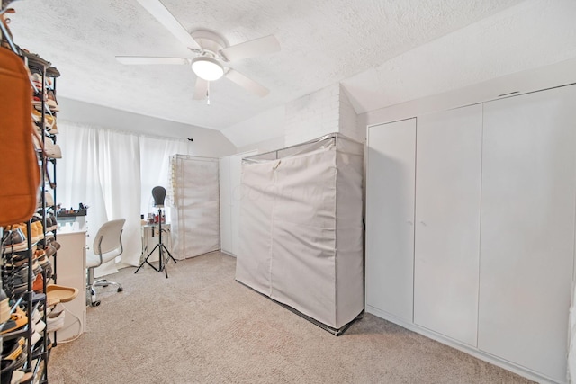 interior space featuring carpet flooring, a textured ceiling, vaulted ceiling, a ceiling fan, and a closet