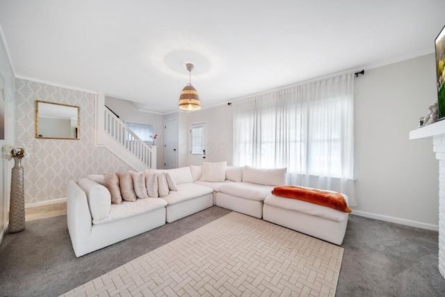 carpeted living area featuring baseboards, ornamental molding, stairs, and a fireplace