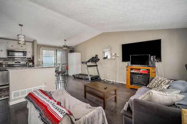 2495 Hingham Ln, Columbus, OH 43224 - living area featuring a textured ceiling, vaulted ceiling, dark wood finished floors, a ceiling fan, and baseboards