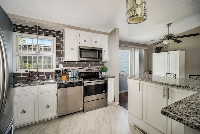2495 Hingham Ln, Columbus, OH 43224 - kitchen with stainless steel appliances, a sink, dark stone countertops, ceiling fan, and tasteful backsplash