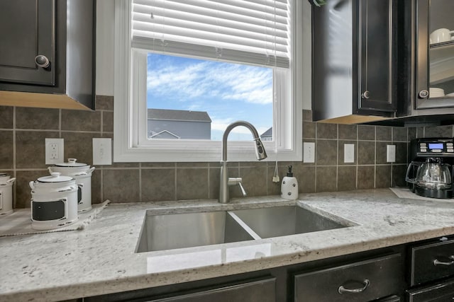 114 Hummock Dr, Etna, OH 43062 - kitchen featuring light stone countertops, glass insert cabinets, a sink, and backsplash
