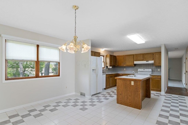kitchen with under cabinet range hood, white appliances, light countertops, and a sink