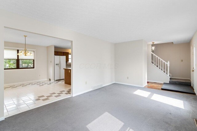 unfurnished living room with a chandelier, stairs, baseboards, and light carpet