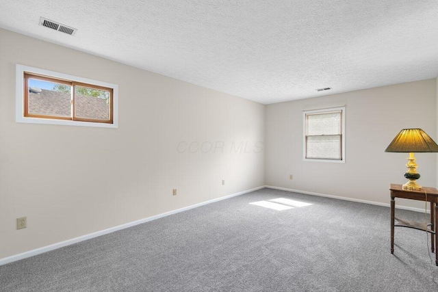 carpeted spare room with plenty of natural light, baseboards, and a textured ceiling