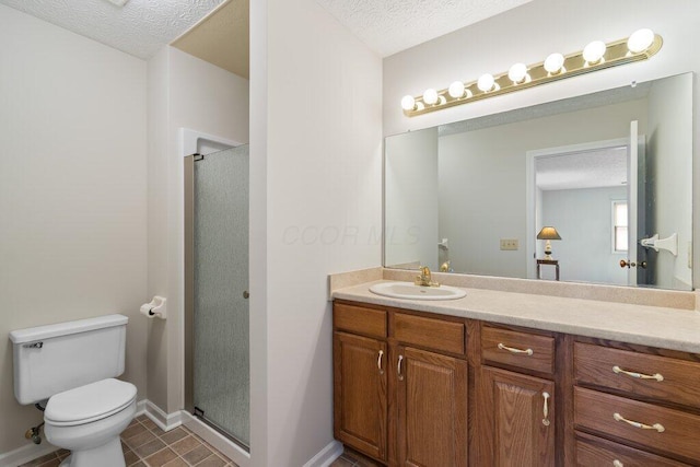 bathroom featuring a stall shower, toilet, vanity, baseboards, and a textured ceiling