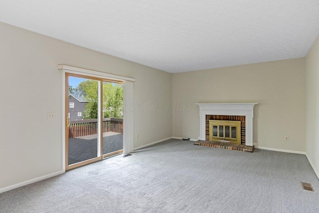 unfurnished living room with carpet flooring, baseboards, a brick fireplace, and a textured ceiling