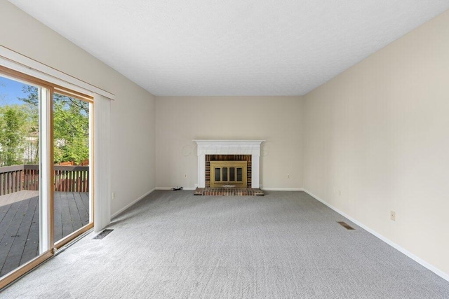 unfurnished living room featuring carpet floors, a fireplace, baseboards, and a textured ceiling