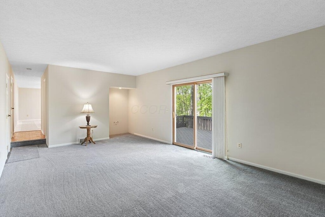 empty room with carpet, baseboards, and a textured ceiling