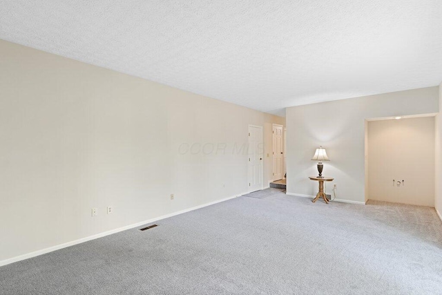 spare room featuring carpet flooring, baseboards, and a textured ceiling