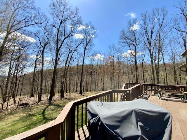 wooden terrace featuring a forest view and area for grilling