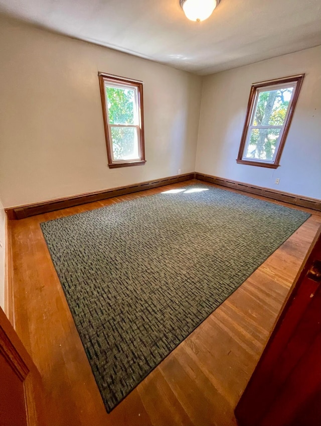 unfurnished room with baseboards, a healthy amount of sunlight, and wood finished floors
