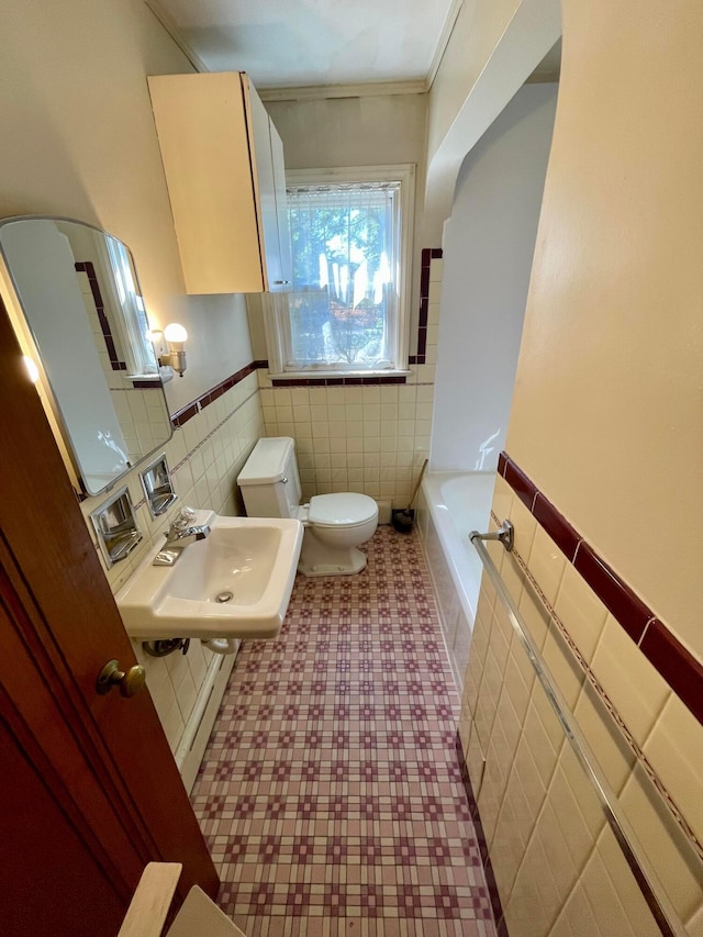 bathroom with a washtub, tile patterned floors, a sink, tile walls, and toilet