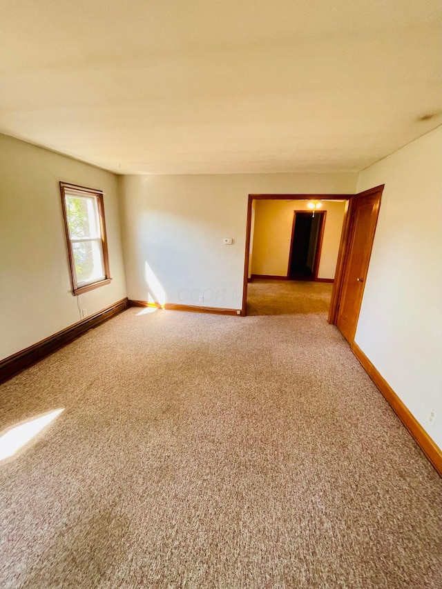 unfurnished room with baseboards and light carpet