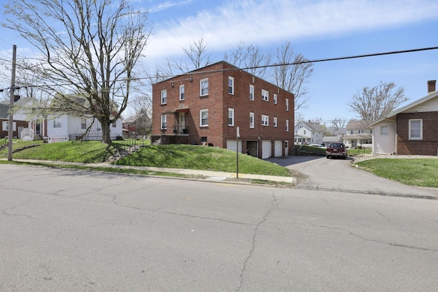 view of front of house with an attached garage, a front lawn, driveway, and a residential view