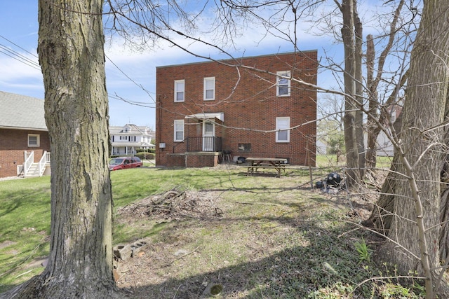 rear view of property featuring brick siding and a yard