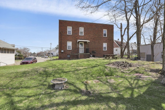 rear view of property featuring a lawn and brick siding