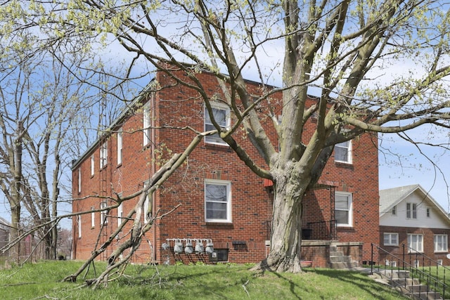 back of property featuring brick siding and a yard