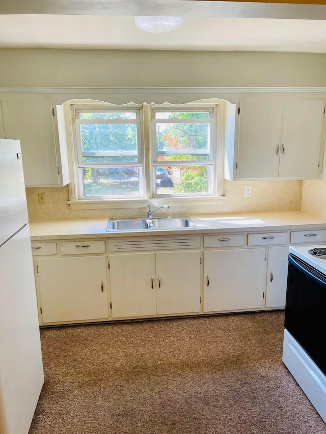 kitchen featuring freestanding refrigerator, plenty of natural light, electric range, and a sink