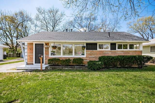 single story home with stone siding, a shingled roof, and a front yard