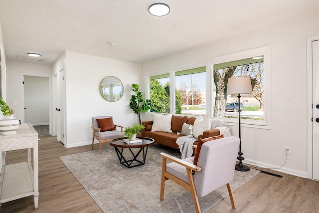 living area featuring baseboards, wood finished floors, and a textured ceiling