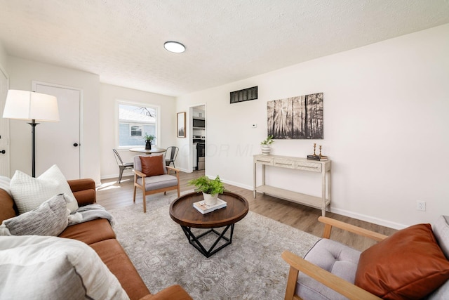 living area featuring baseboards, wood finished floors, and a textured ceiling