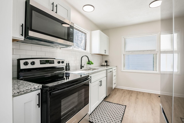 kitchen featuring white cabinets, a sink, appliances with stainless steel finishes, and tasteful backsplash