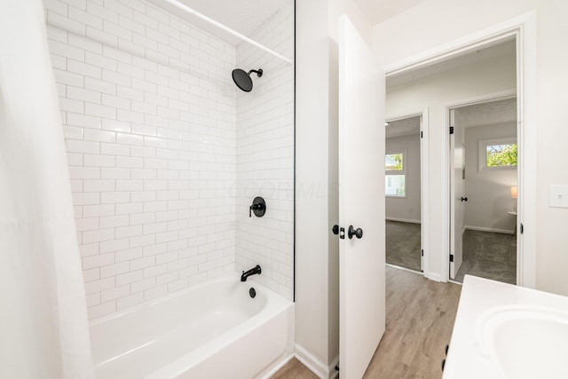 full bathroom with baseboards, wood finished floors, a sink, and shower / bathtub combination with curtain