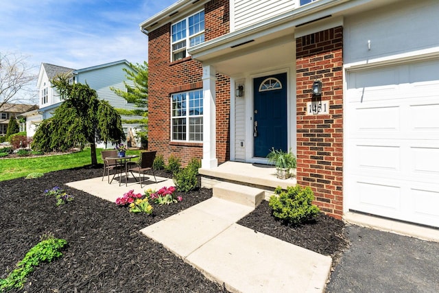 doorway to property with an attached garage and brick siding