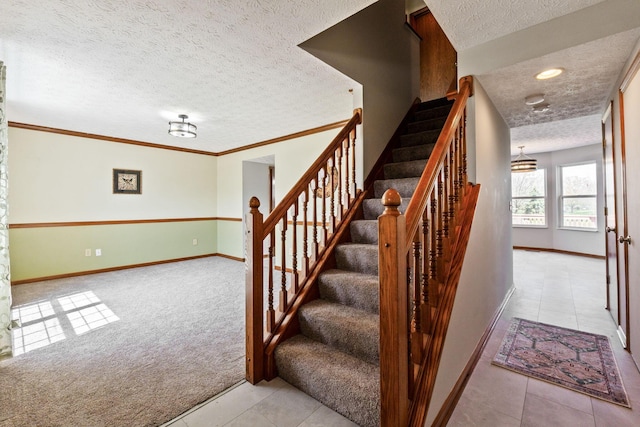 staircase with tile patterned floors, baseboards, a textured ceiling, and carpet flooring