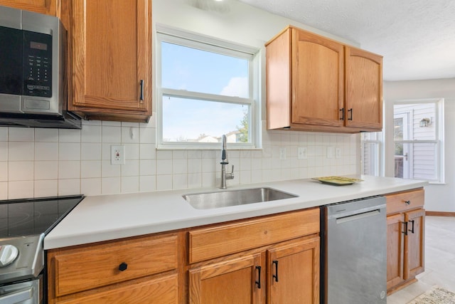 kitchen with light countertops, a sink, backsplash, and appliances with stainless steel finishes