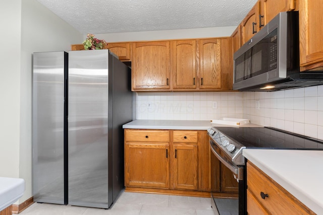 kitchen featuring backsplash, brown cabinets, appliances with stainless steel finishes, and light countertops