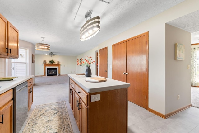 kitchen featuring light countertops, stainless steel dishwasher, baseboards, a fireplace, and a textured ceiling