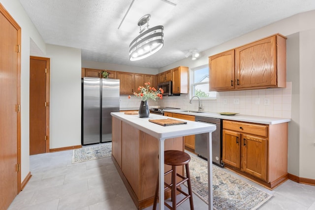 kitchen featuring light countertops, decorative backsplash, stainless steel appliances, and a sink