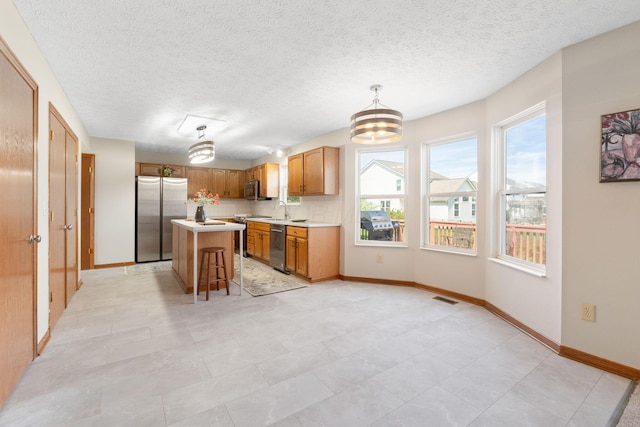 kitchen with stainless steel appliances, a sink, visible vents, an inviting chandelier, and light countertops