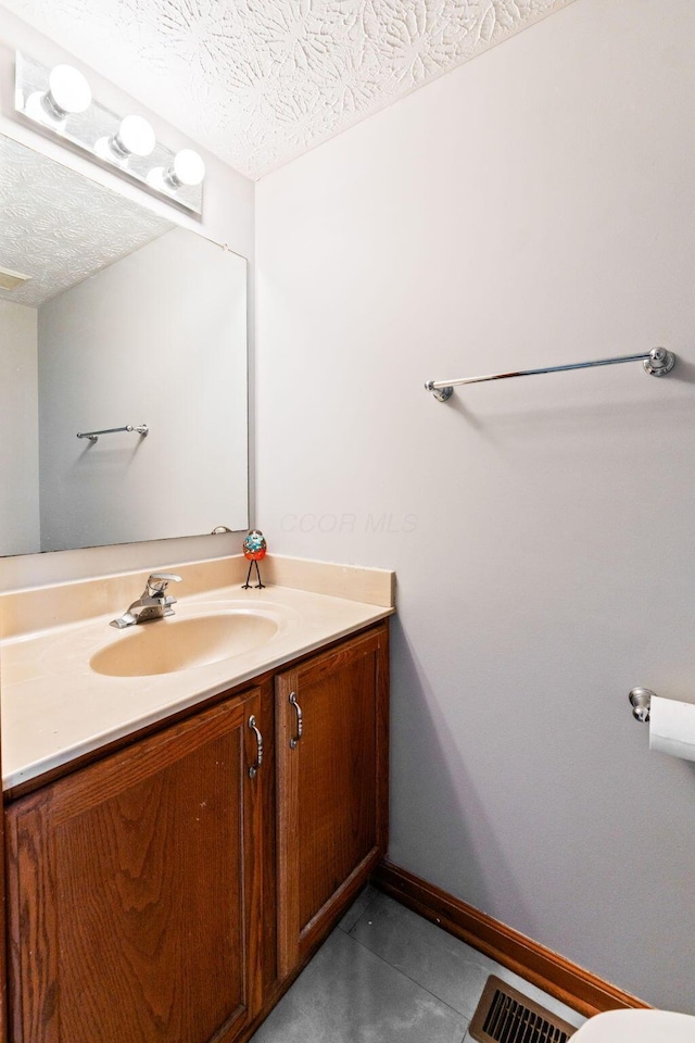 bathroom featuring baseboards, vanity, a textured ceiling, and visible vents