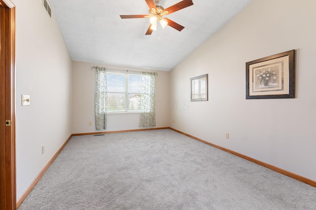 carpeted empty room featuring lofted ceiling, visible vents, baseboards, and ceiling fan
