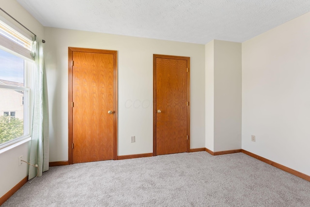 unfurnished bedroom featuring baseboards, carpet floors, and a textured ceiling