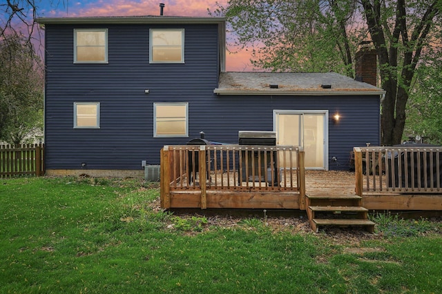 back of house featuring a lawn, fence, a chimney, and a deck