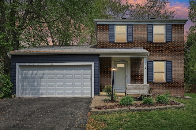 traditional-style home featuring brick siding, a garage, and aphalt driveway