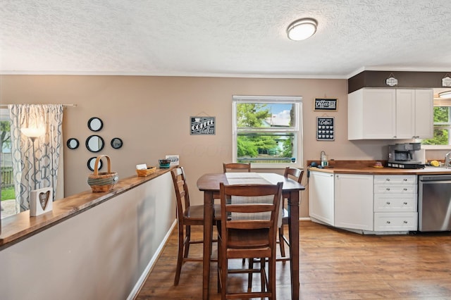kitchen with stainless steel dishwasher, a textured ceiling, white cabinets, and light wood-type flooring